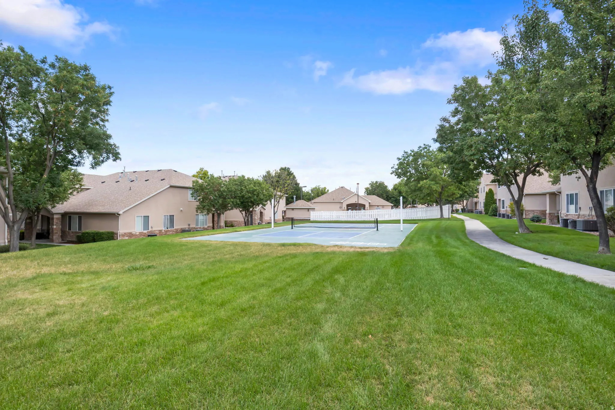 Expansive green space featuring a tennis court and mature shade trees