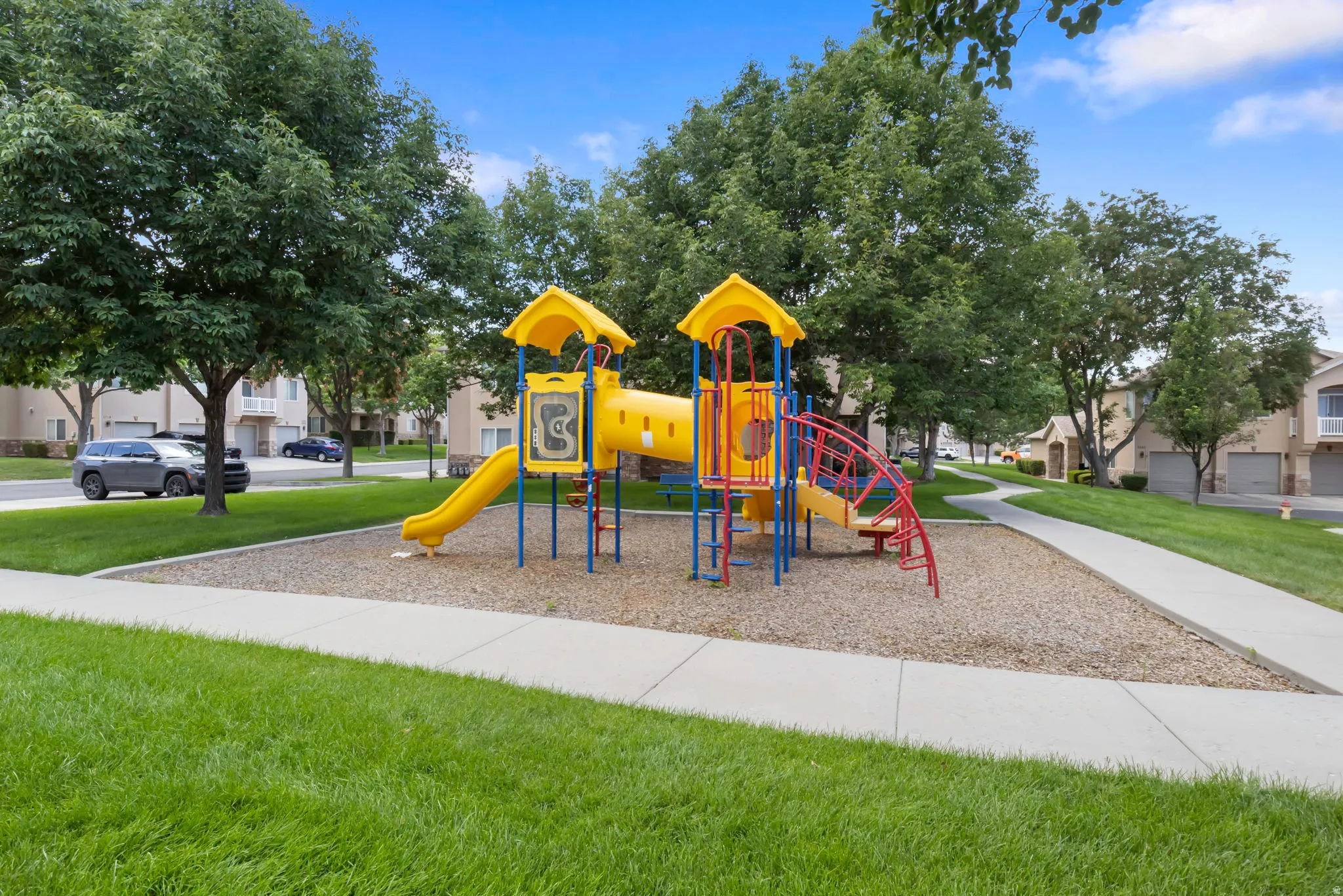 Community playground featuring a multi-level structure with slides and climbing elements outside your patio door and front door!