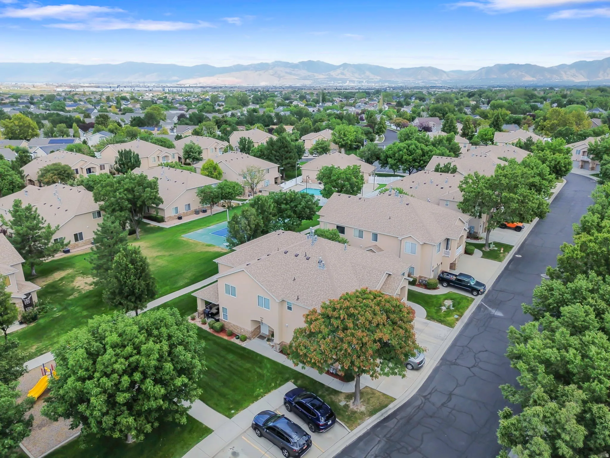 Residential community featuring stucco exteriors, shingle roofing, mature trees, and paved roadways
