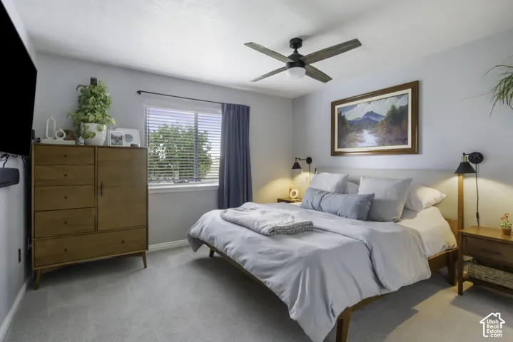 Primary bedroom with neutral wall color, wall-mounted light fixtures, window with blinds, ceiling fan