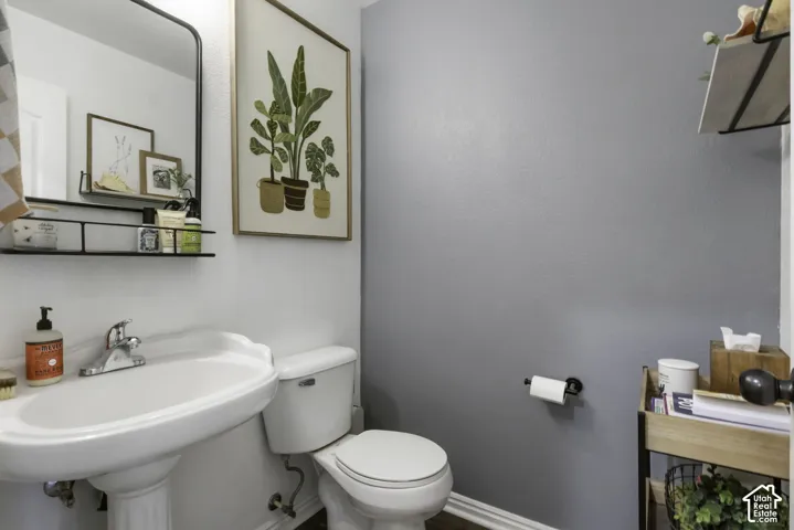 Half bath pedestal sink with chrome faucet, wall-mounted mirror with integrated shelving, and wood-finish flooring