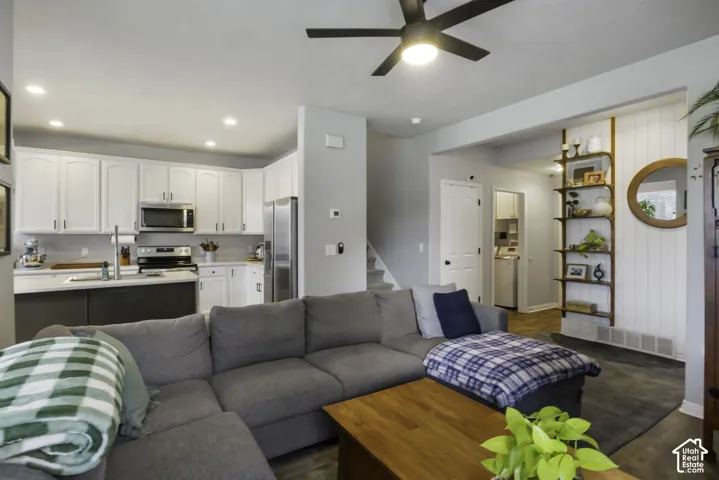 Open-concept living area featuring a ceiling fan, wood-finish flooring, and a kitchen.