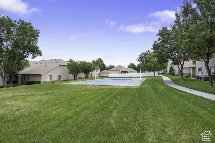 Expansive green space featuring a tennis court and mature shade trees