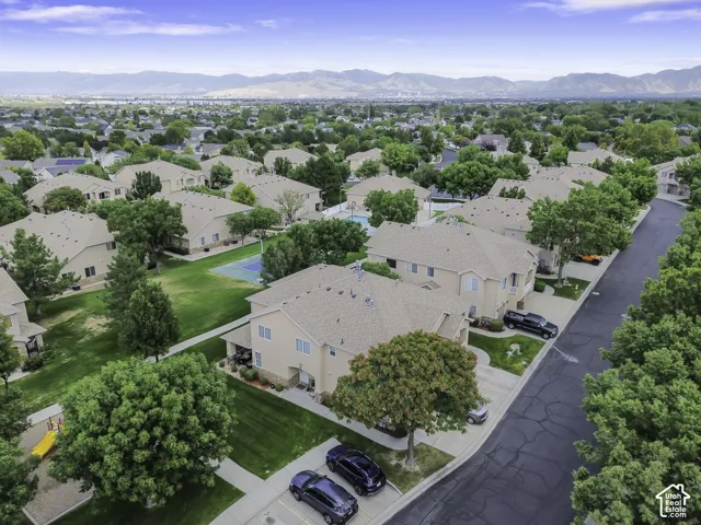 Residential community featuring stucco exteriors, shingle roofing, mature trees, and paved roadways