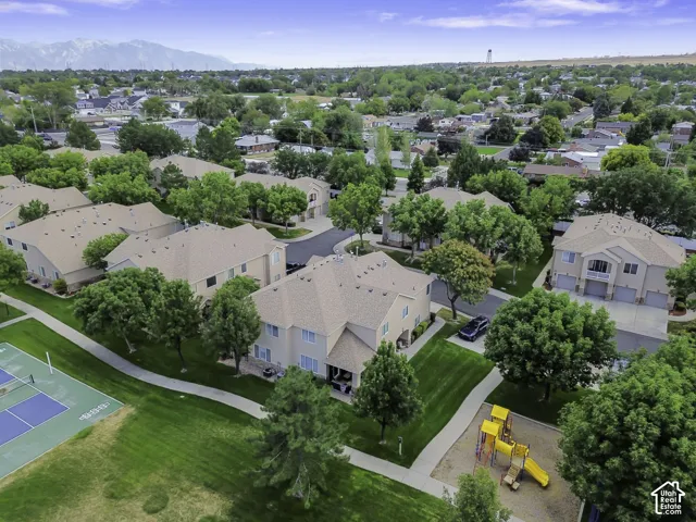 Manicured green spaces, paved walking paths, a playground structure, and a tennis court