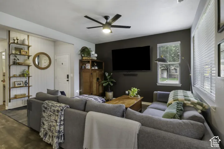 Spacious living area featuring a dark accent wall, wood-finish flooring, and a ceiling fan