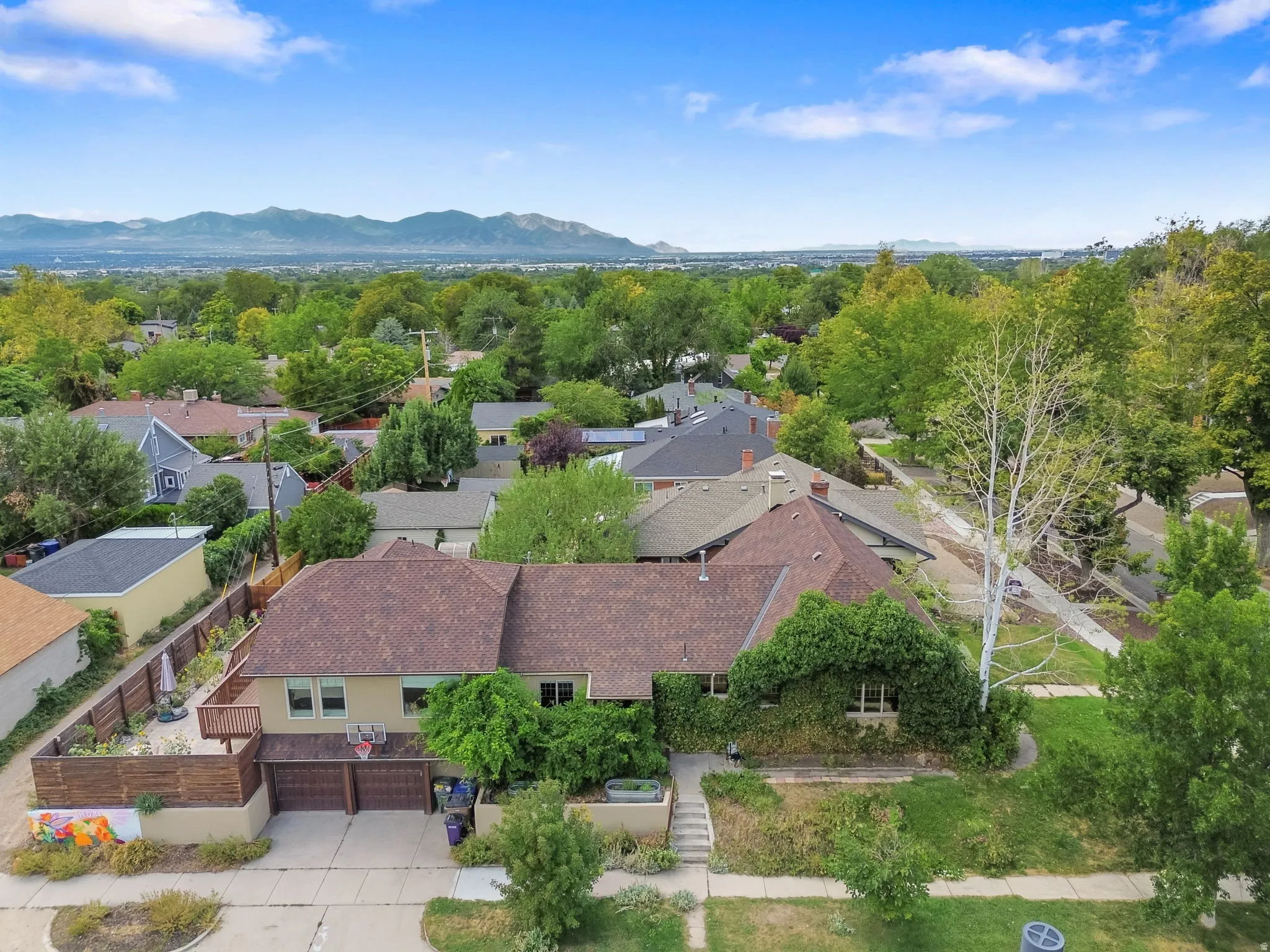 Residential property with an attached two-car garage, mature landscaping, and a mountain backdrop