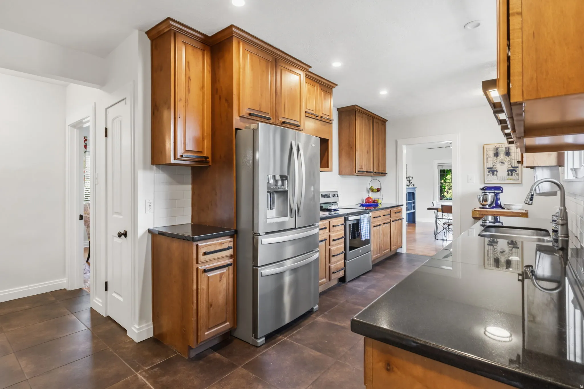 Kitchen featuring wood cabinetry, stainless steel appliances, dark countertops, a white subway tile backsplash, and recessed lighting