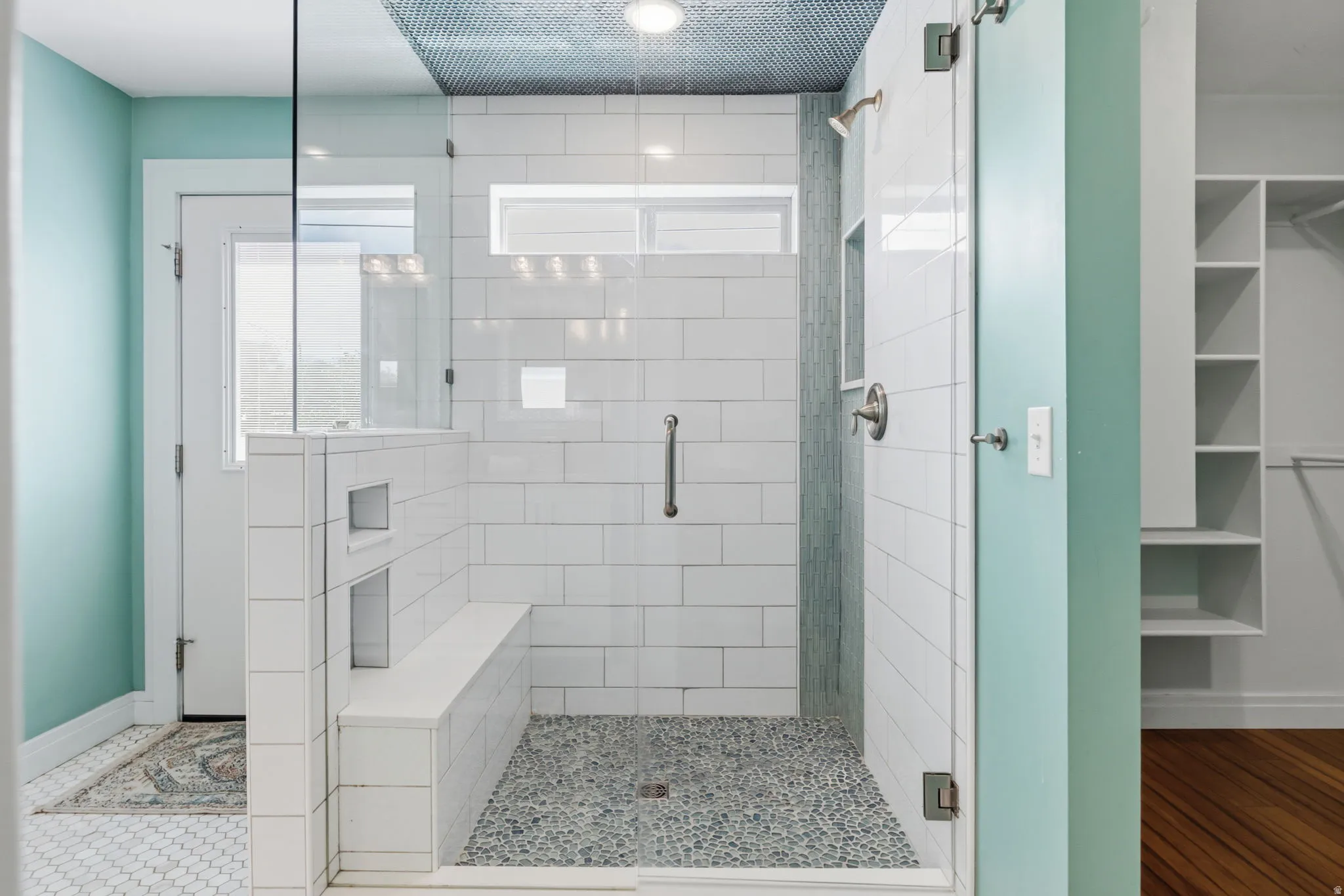 Primary suite Spa-inspired primary bathroom featuring a frameless glass-enclosed shower with subway tile surround, rainfall showerhead, built-in bench seating, and pebble stone flooring