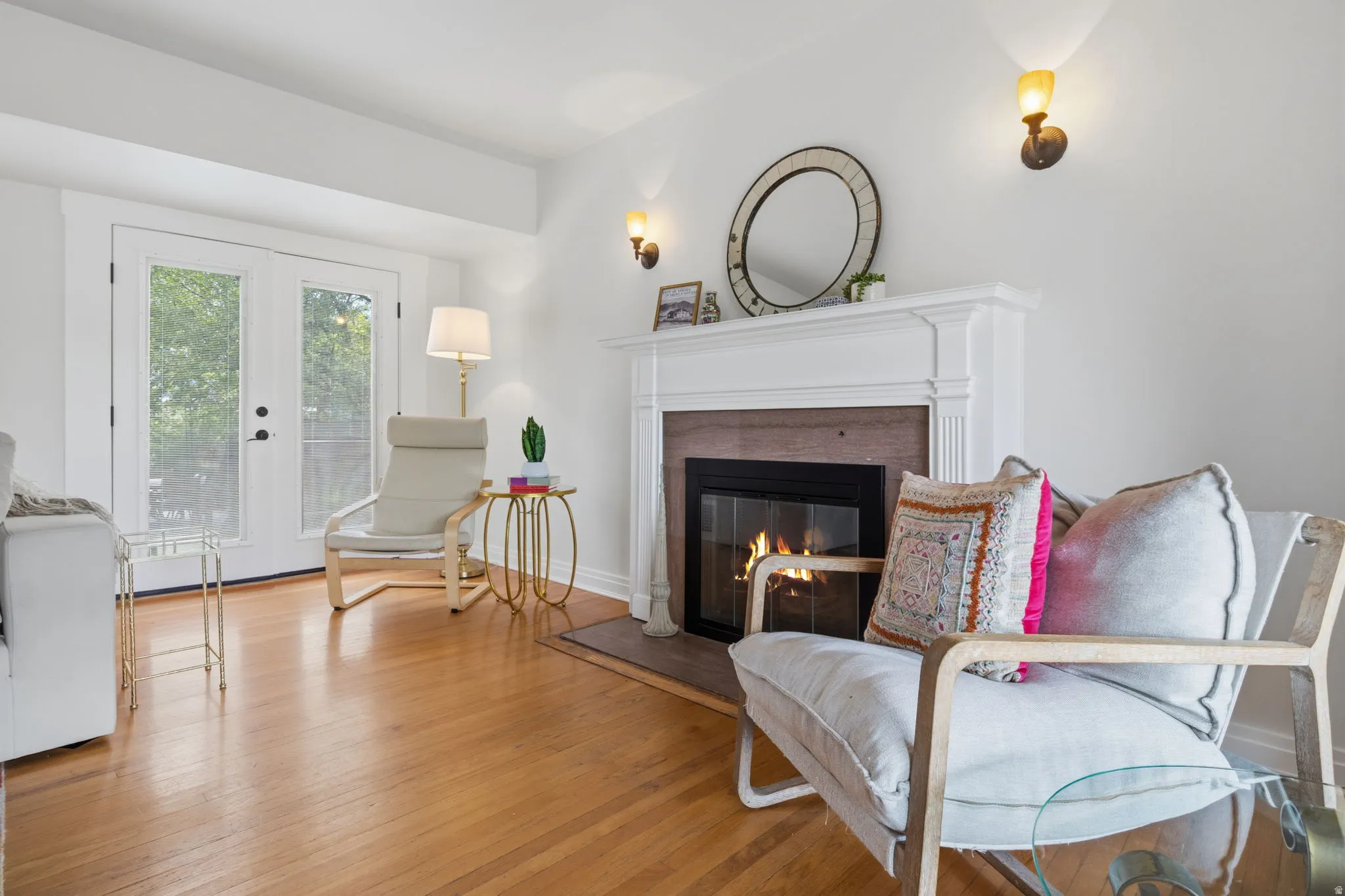 French doors, gas fireplace with white mantel, two wall sconces
