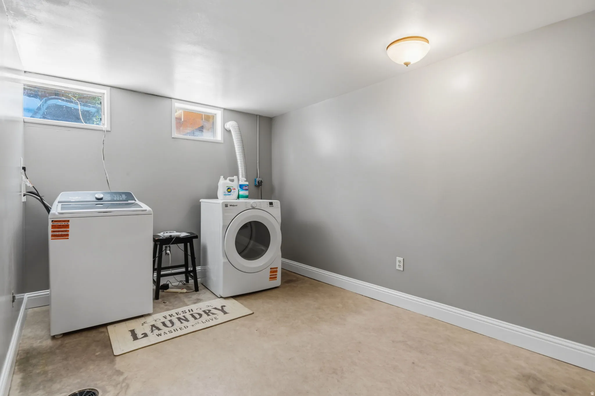 Utility area featuring a top-load washer, front-load dryer, and two windows