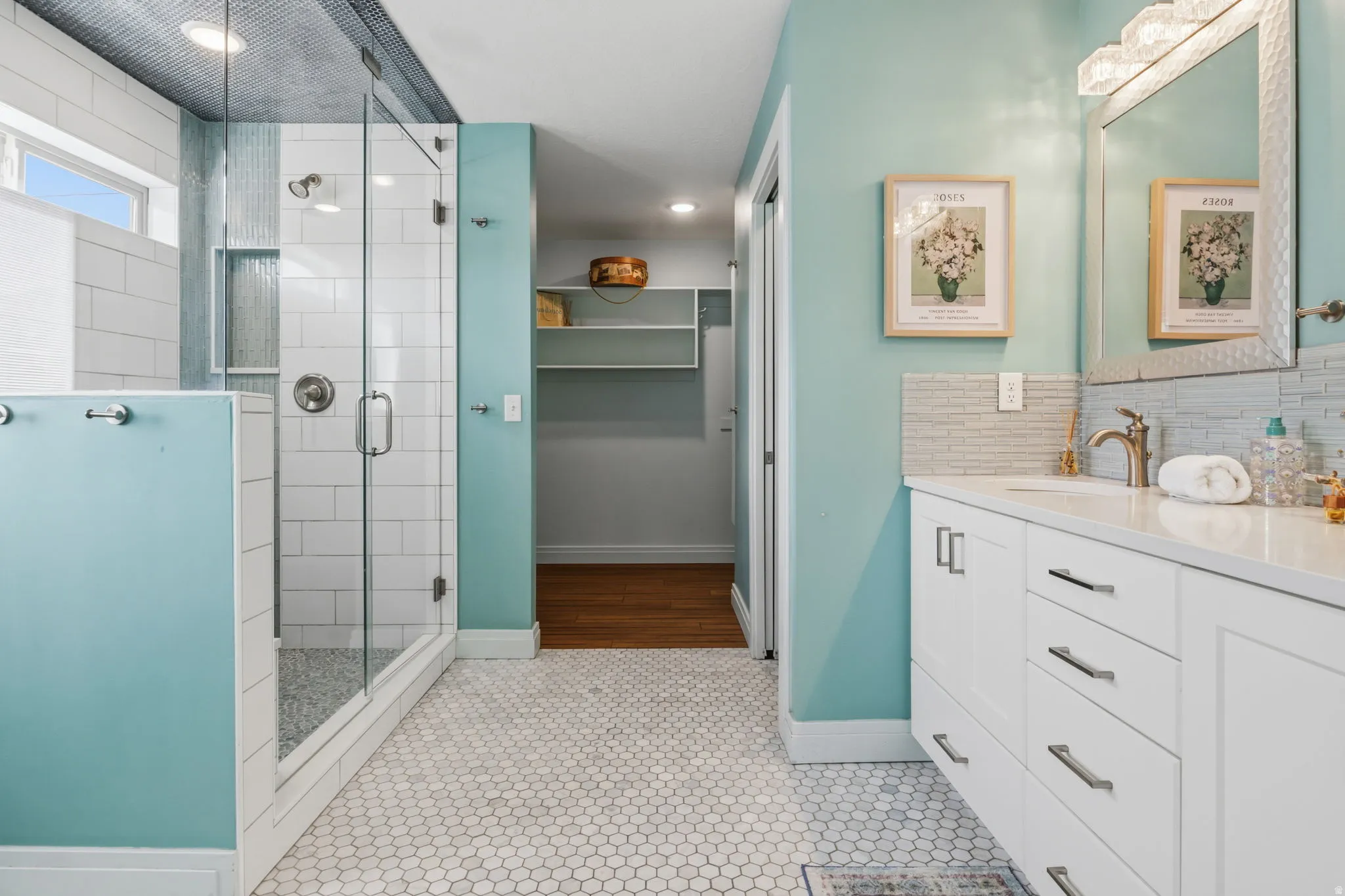 Bathroom featuring a glass-enclosed shower, white subway tile, white hexagon mosaic floor tile, and a double vanity with white cabinetry