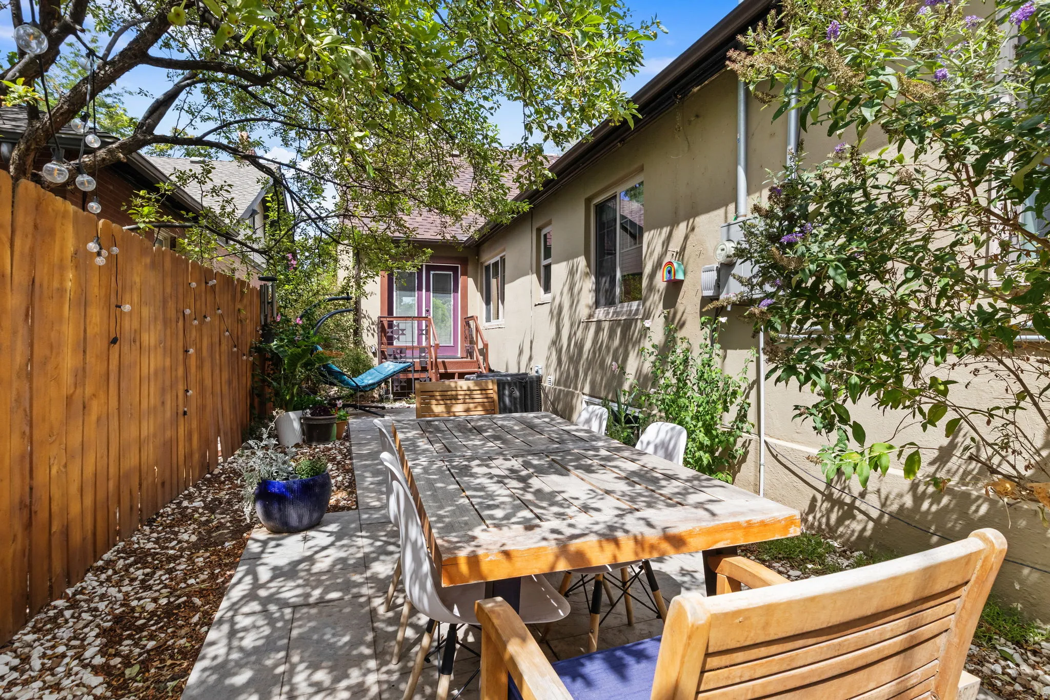 Private outdoor patio with a wood privacy fence, mature trees, and a raised wood deck
