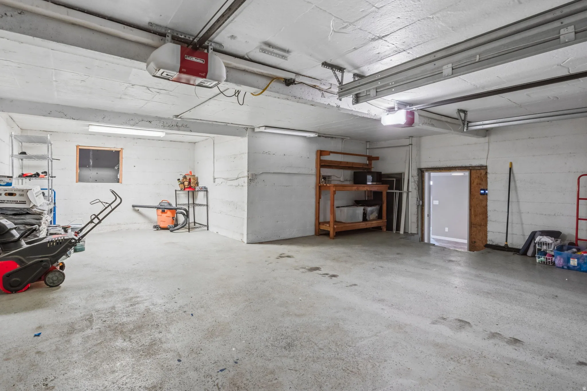 Spacious garage with concrete flooring, overhead lighting, and an overhead garage door opener