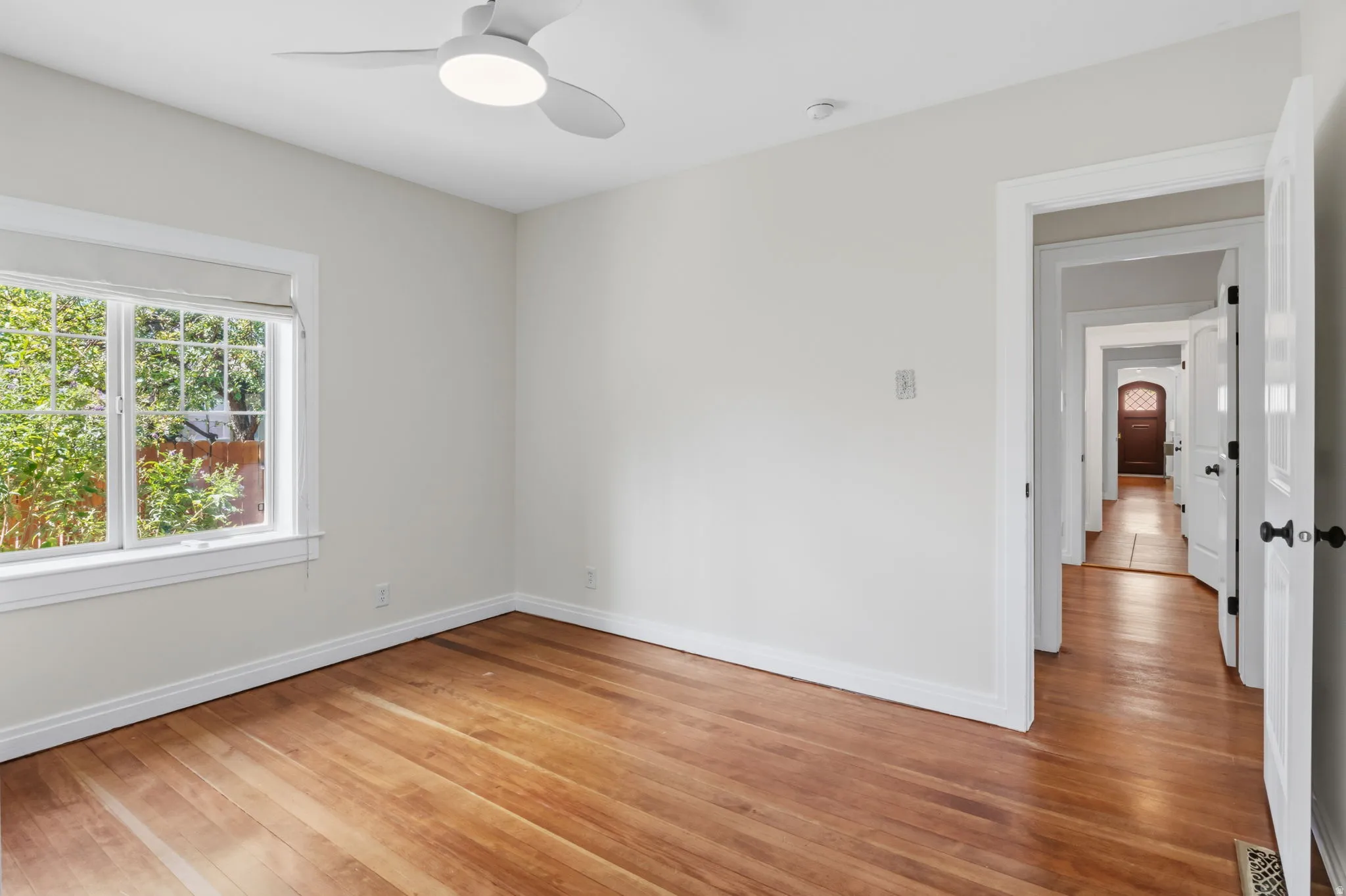 Bedroom 2 Hardwood flooring, white walls, double-pane window, modern ceiling fan, and white trim throughout