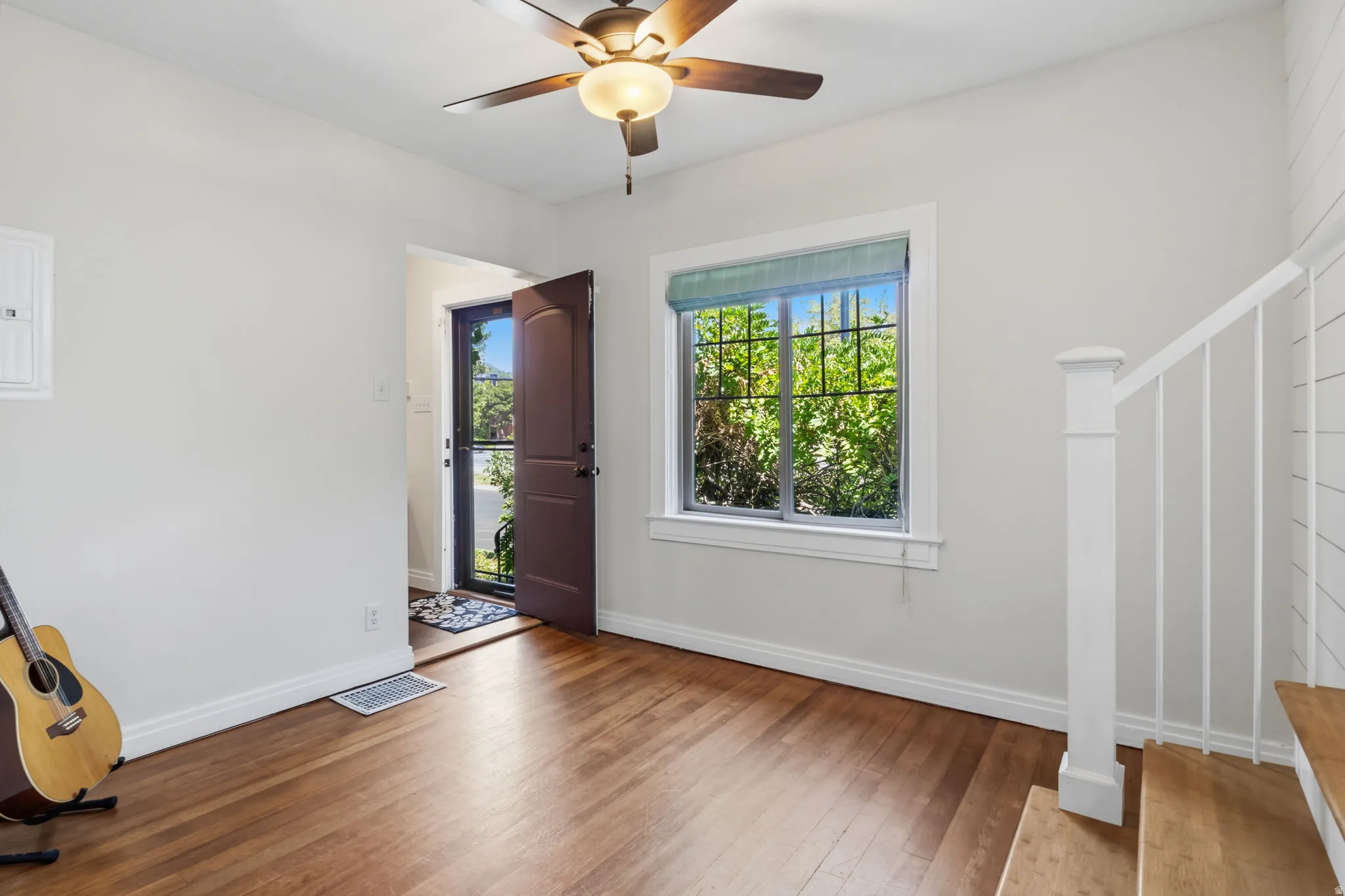 Wood flooring, ceiling fan with integrated lighting, white trim, and white walls