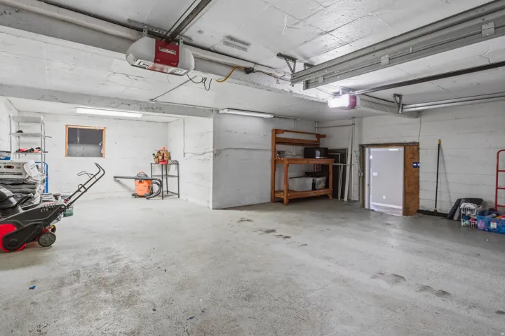 Spacious garage with concrete flooring, overhead lighting, and an overhead garage door opener