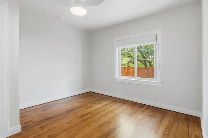 Bedroom 2 Hardwood flooring with white walls, a white ceiling fan, and a window with white trim
