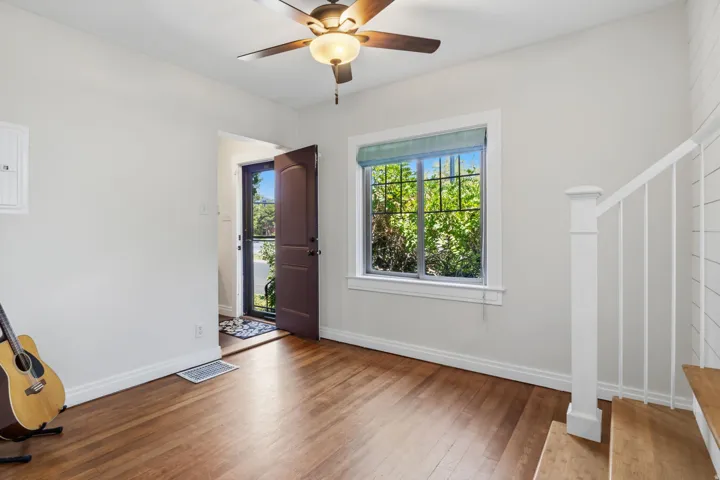 Wood flooring, ceiling fan with integrated lighting, white trim, and white walls