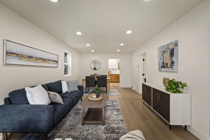 Recessed lighting illuminates the open living and dining areas featuring wood-finish flooring and neutral wall tones