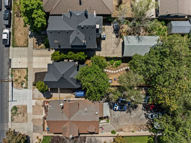 Property featuring multiple structures with dark shingle roofs, paved driveways, and mature landscaping