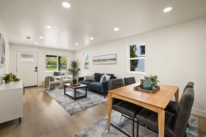 Recessed lighting illuminates the open-concept living space, featuring wood-finish flooring and multiple windows
