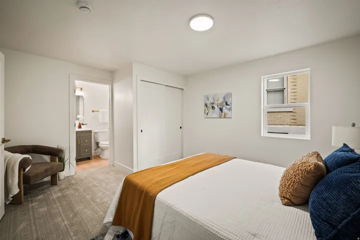 Spacious primary bedroom with recessed ceiling lighting, dual closets with sliding doors, and neutral wall finishes