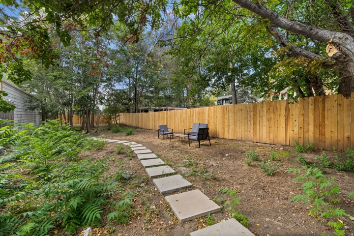 Expansive outdoor space featuring a wood fence, concrete stepping stone pathway, and mature trees