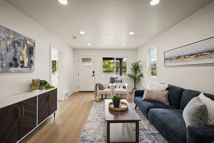 Recessed ceiling lighting, wood-finish flooring, white walls, and a built-in console cabinet with gold hardware