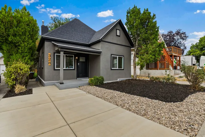 Stucco exterior with a covered entry, dark-framed windows, and a paved driveway