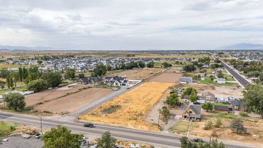 Expansive land parcel featuring a paved road frontage, surrounded by established residential areas and open fields