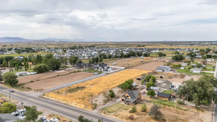Expansive undeveloped lot with street frontage, surrounded by established residences and distant mountain scenery