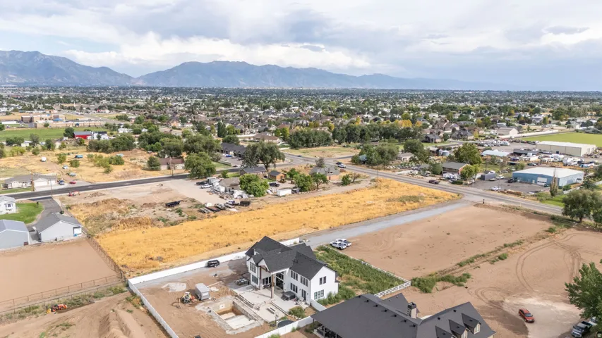 Expansive land parcel featuring partial construction of a multi-story residence, surrounding undeveloped plots, and distant mountain scenery