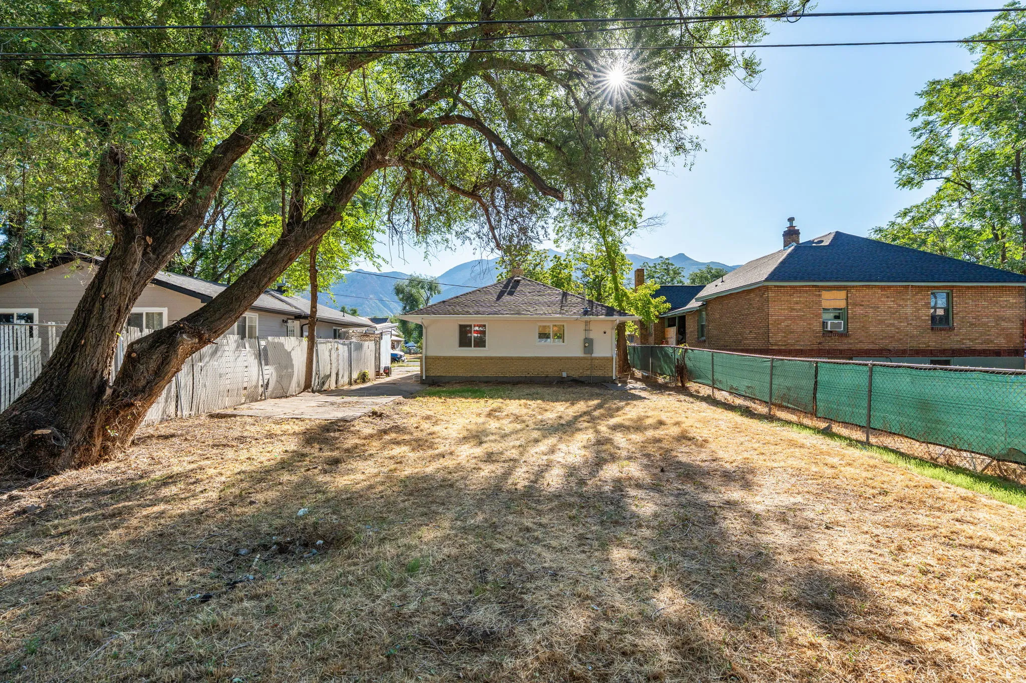 Expansive yard space with mature trees, mountain backdrop, and partial fencing