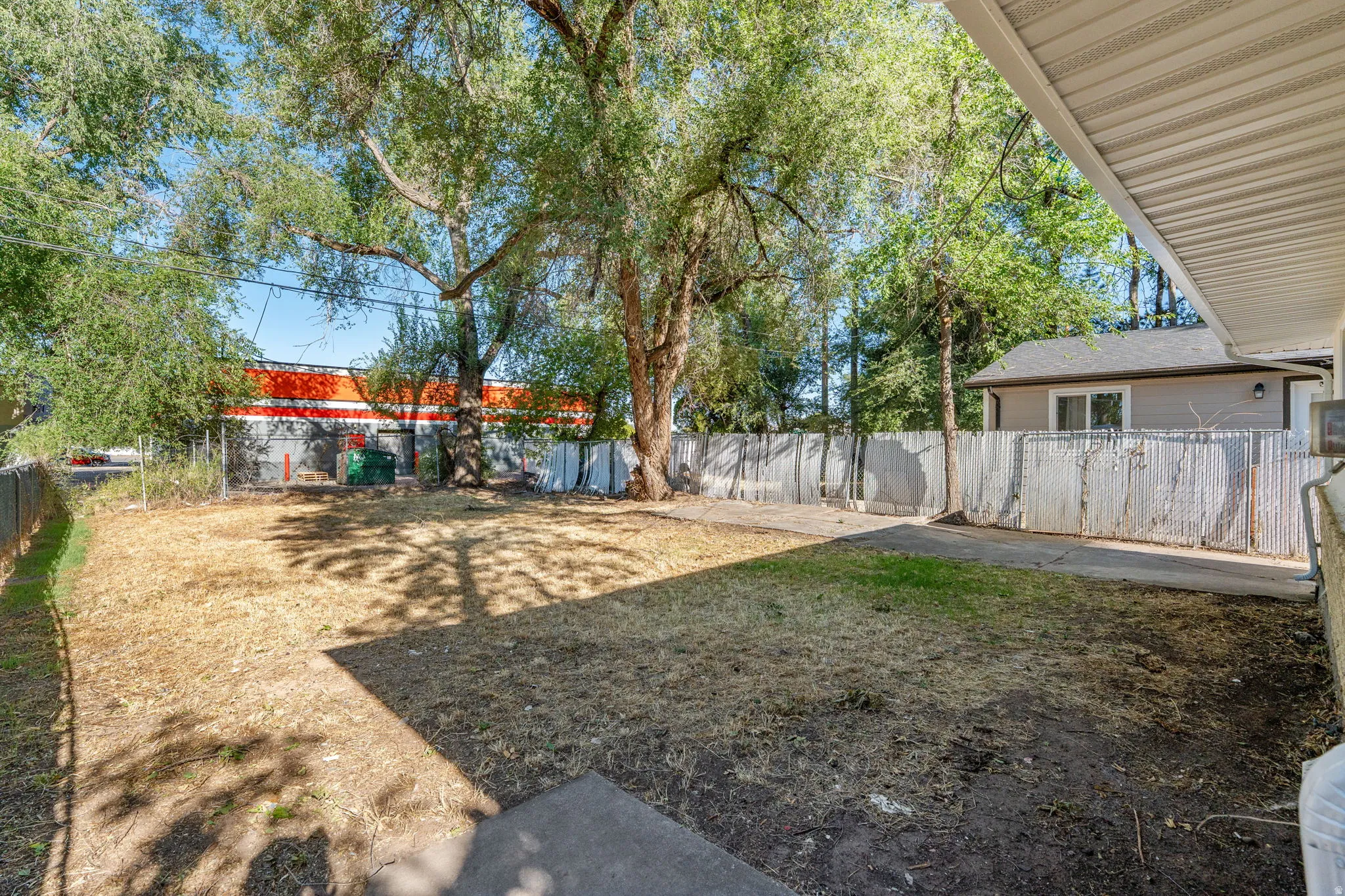 Expansive yard space featuring mature trees and partial fencing