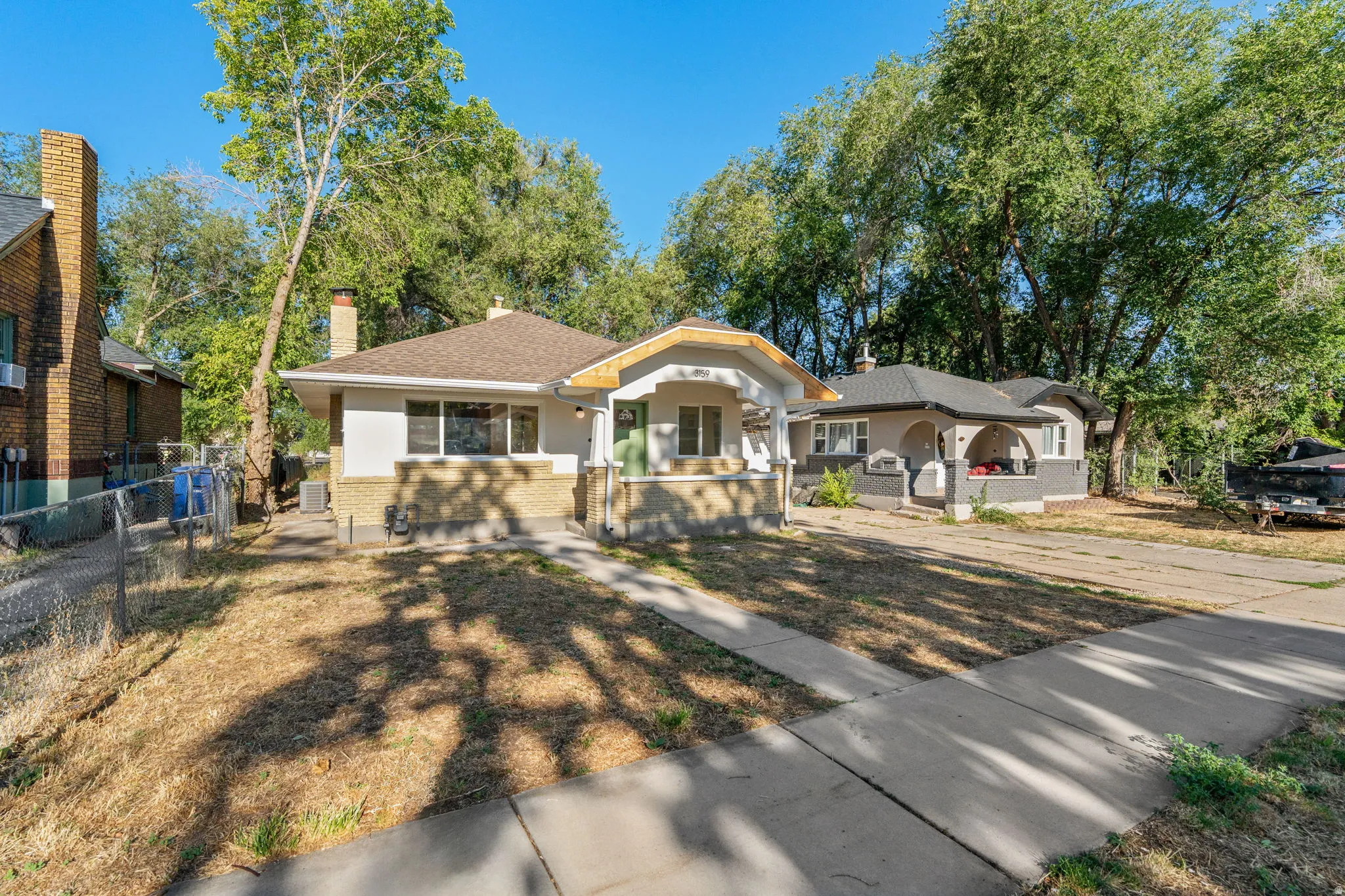 Single-story residence featuring a covered front porch with columns, a multi-pane window, and a light-colored exterior with a brick-finish foundation