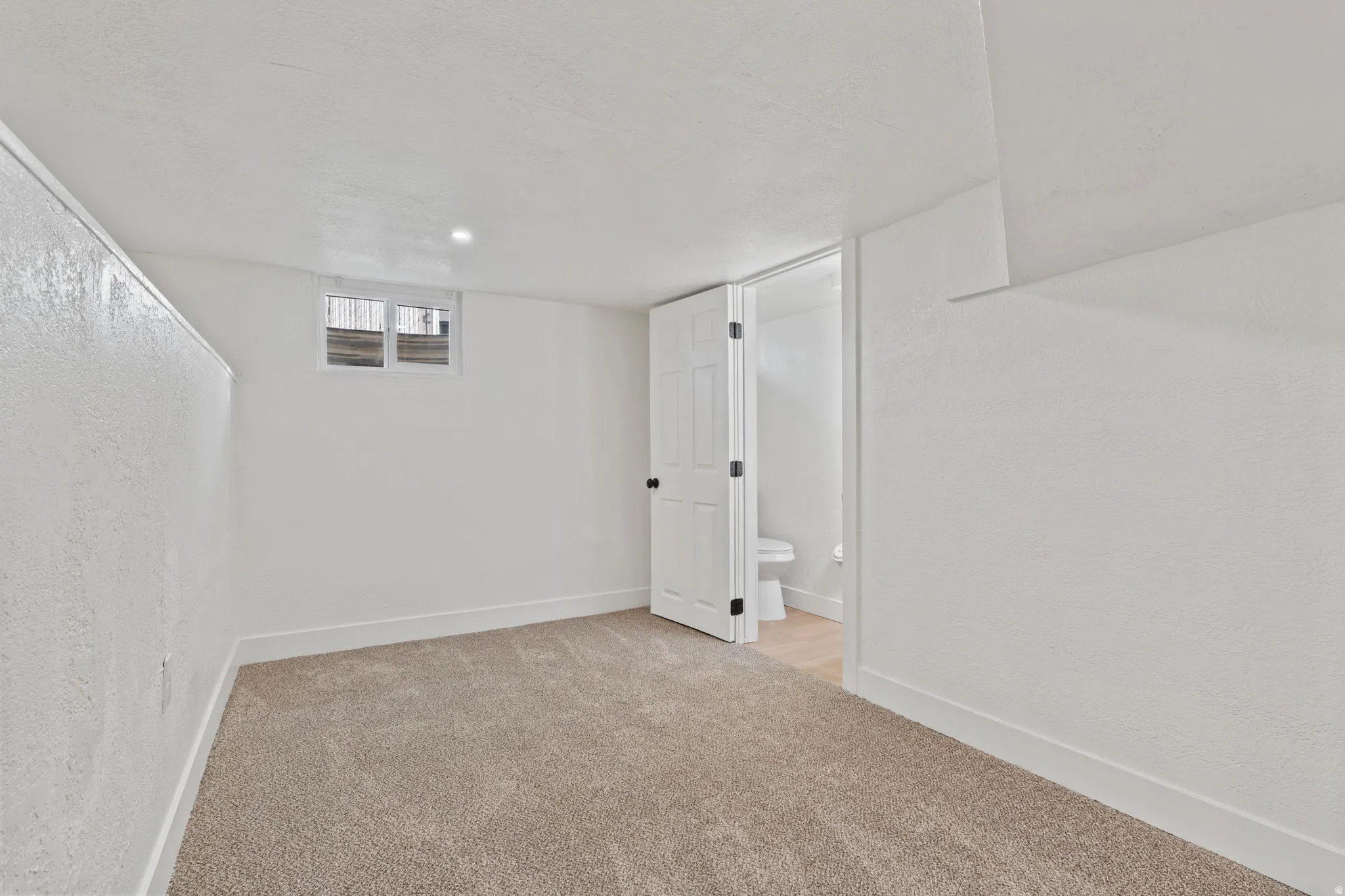 Carpeted flooring, white walls, recessed lighting, white trim, and a white interior door
