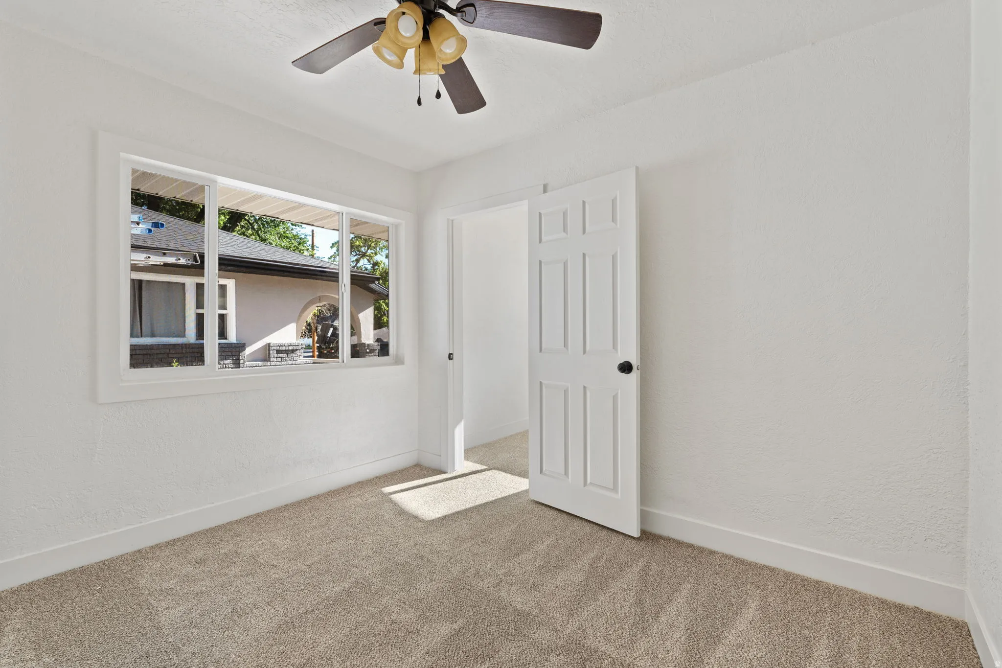 Neutral wall finishes, carpet flooring, a multi-pane window, and a ceiling fan with integrated lighting