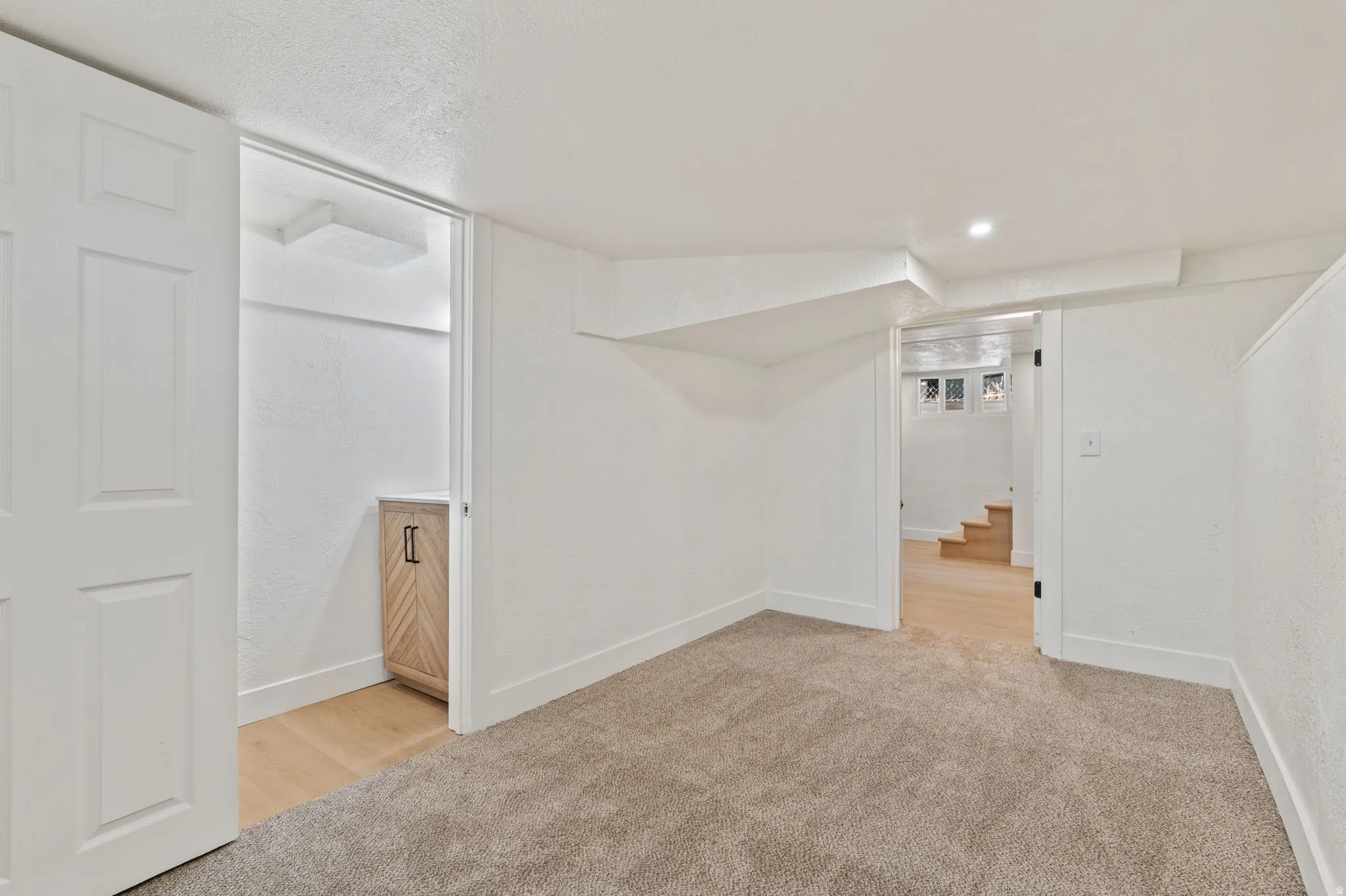 Neutral tone carpeting, recessed lighting, and white textured walls