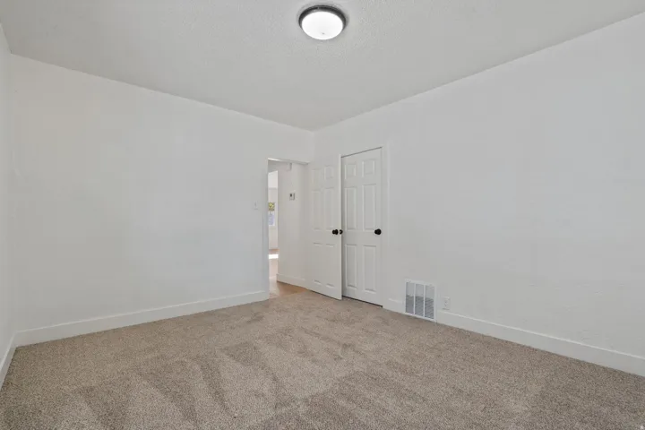 Neutral-toned carpet flooring, white painted walls, and a flush-mount ceiling light fixture