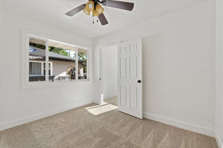 Neutral wall finishes, carpet flooring, a multi-pane window, and a ceiling fan with integrated lighting