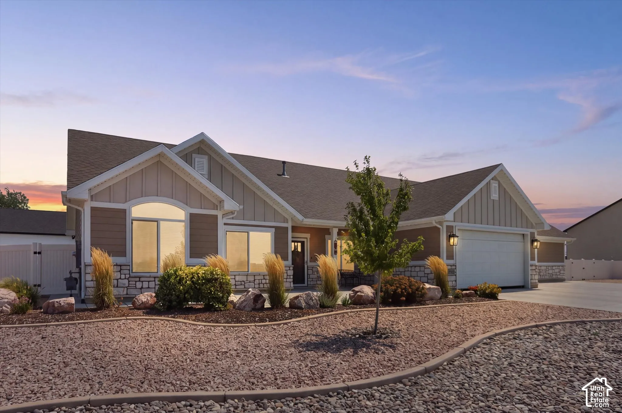 Single-story exterior with a two-car garage, stone facade accents, and a low-maintenance landscape featuring decorative rock and mature plantings