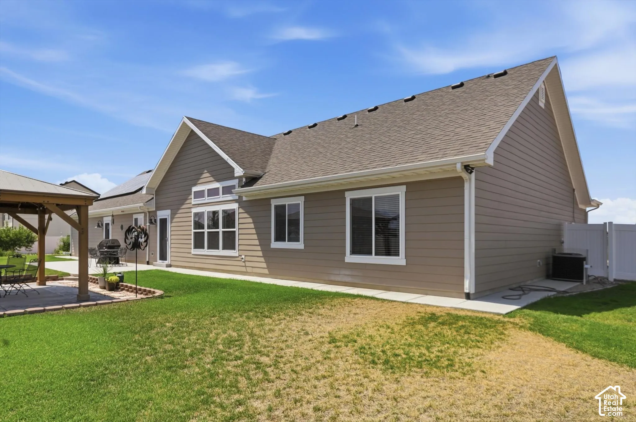 Spacious backyard with a paved patio, a wood pergola, and a privacy fence