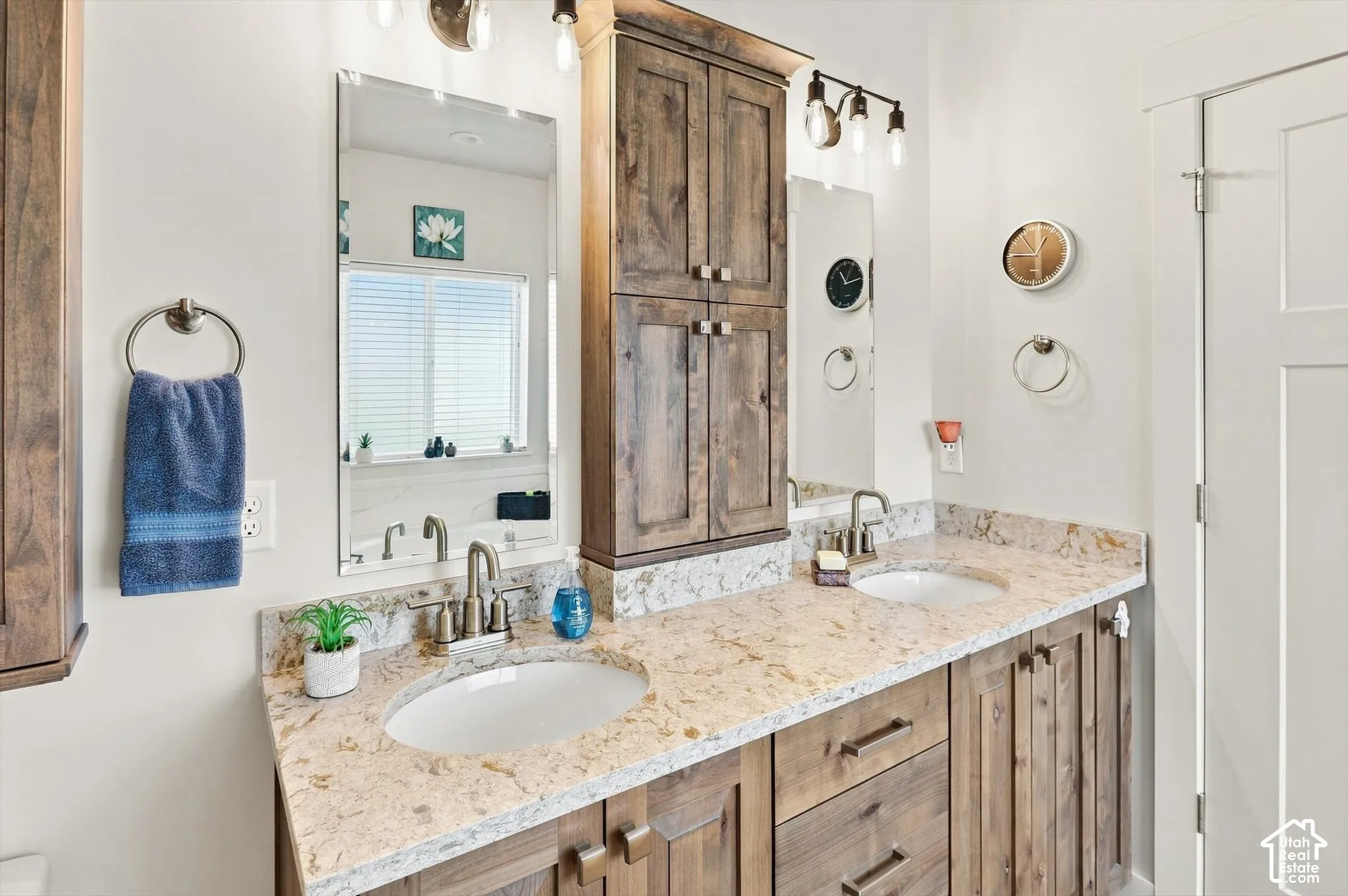 Dual vanity with light-toned countertop, wood-finish cabinetry, and individual mirrors