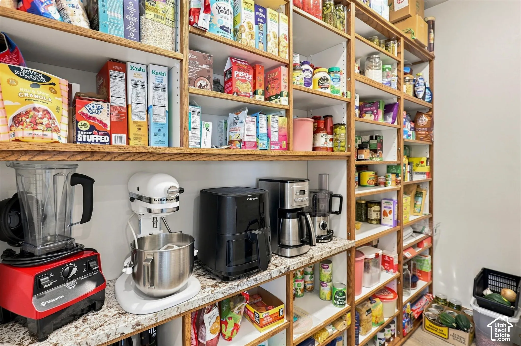 Built-in pantry shelving featuring wood-finish frames and white shelf surfaces, with a granite-style countertop