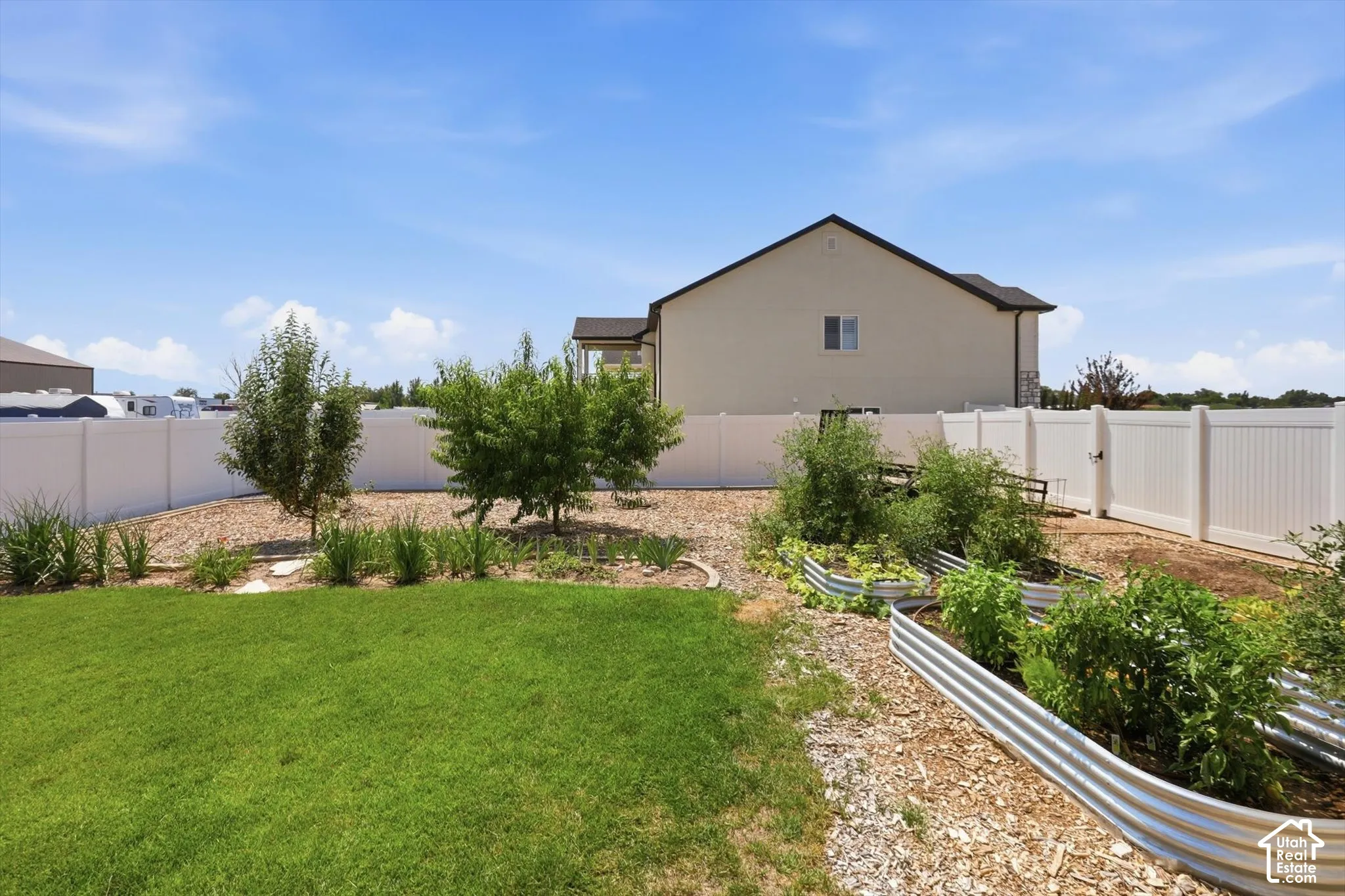 Expansive backyard featuring a manicured lawn, established landscaping, and raised garden beds