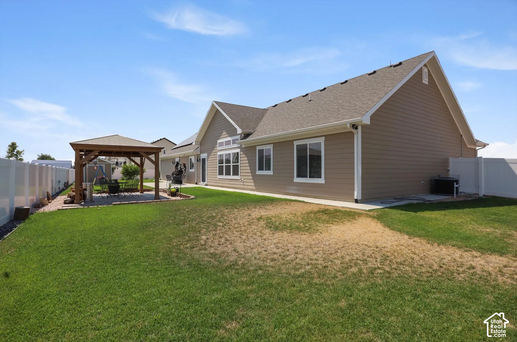 Expansive backyard featuring a gazebo, paver patio, full privacy fencing, and a side patio with concrete surfacing