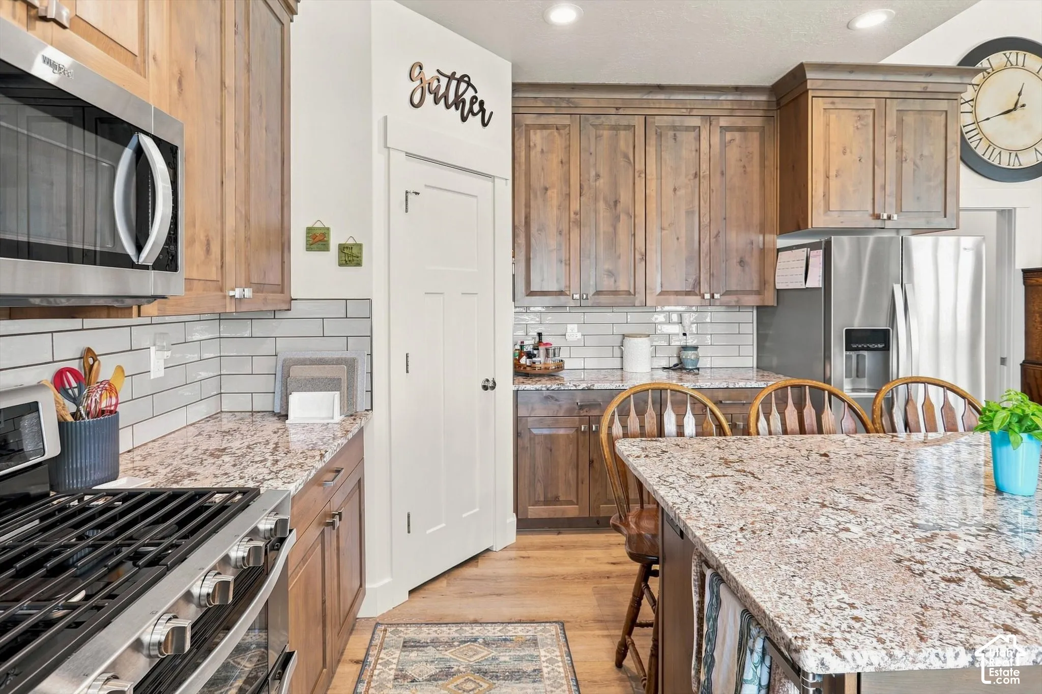 Kitchen featuring wood cabinetry, stainless steel appliances, white subway tile backsplash, and light-colored countertops