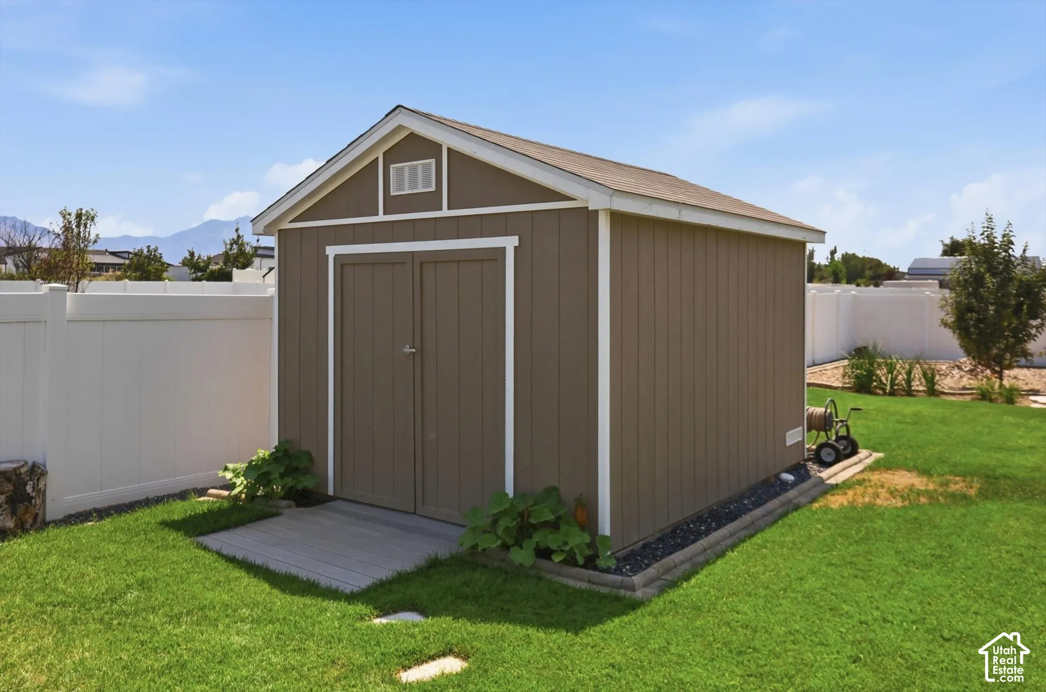 Outdoor storage shed with double doors, wood-look siding, and a gabled roof