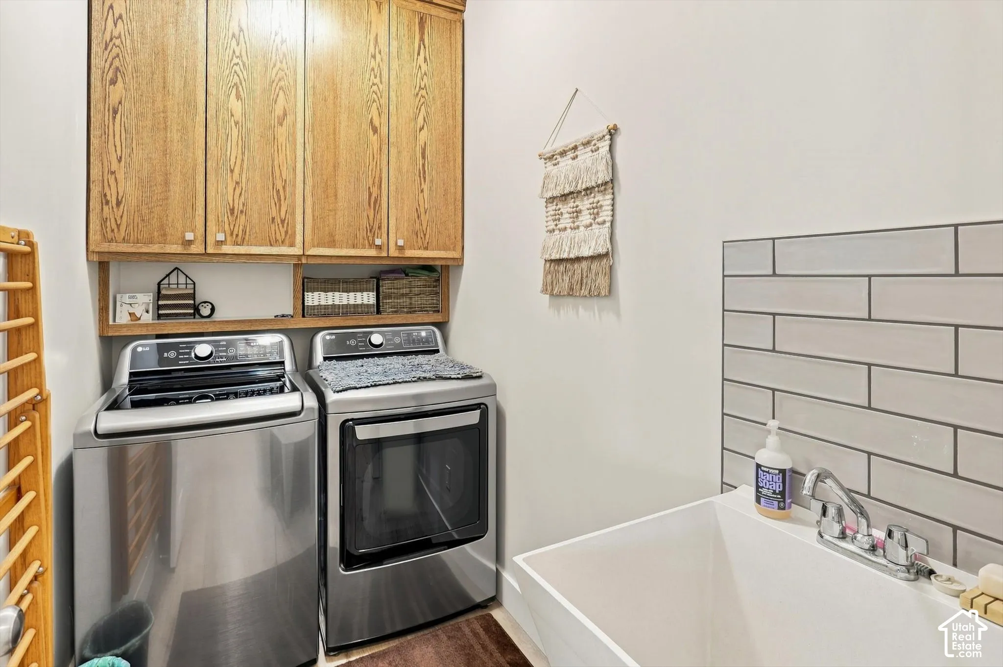 Built-in cabinetry with wood-finish doors, open shelving, and a utility sink with a tiled backsplash